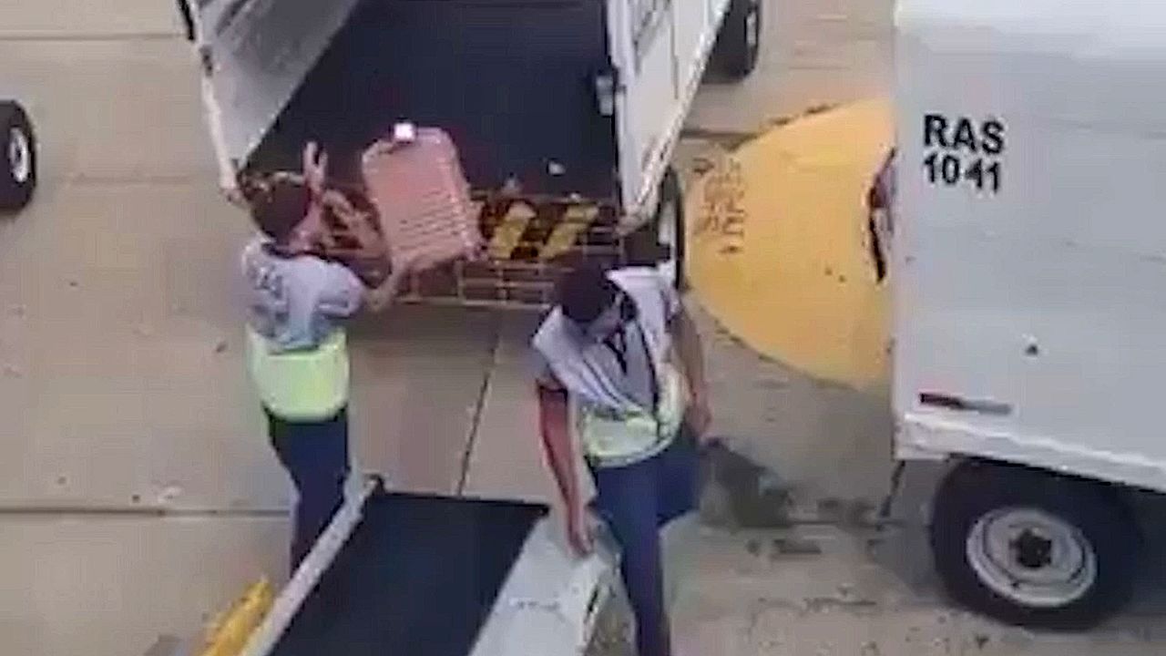 Unsanfte-Gep-ckbehandlung-Flughafenmitarbeiter-schleudert-Koffer-auf-Transportwagen