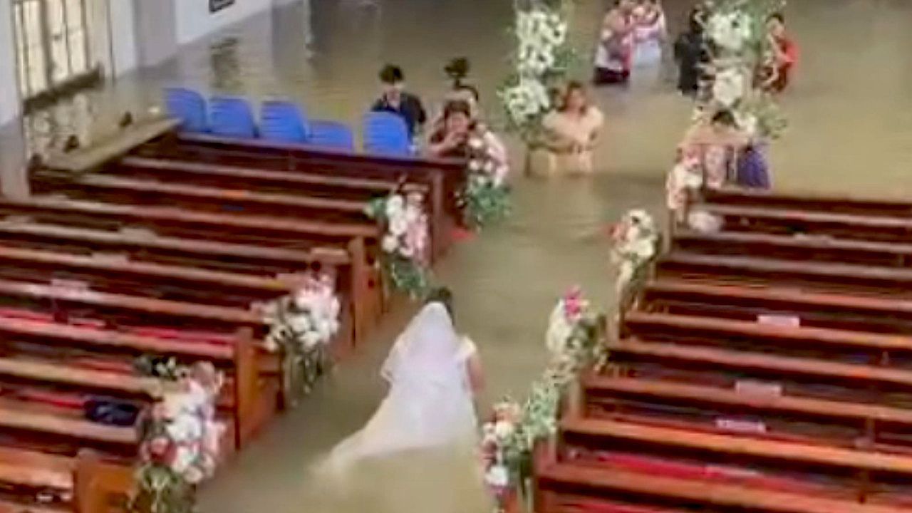 Video: Fluten auf den Philippinen: Braut watet in überschwemmter Kirche zum Altar